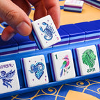 Hand placing a Lunara Scorpio Flower tile next to Aries, songbird One Bam and lion Bam Dragon; rack not included
